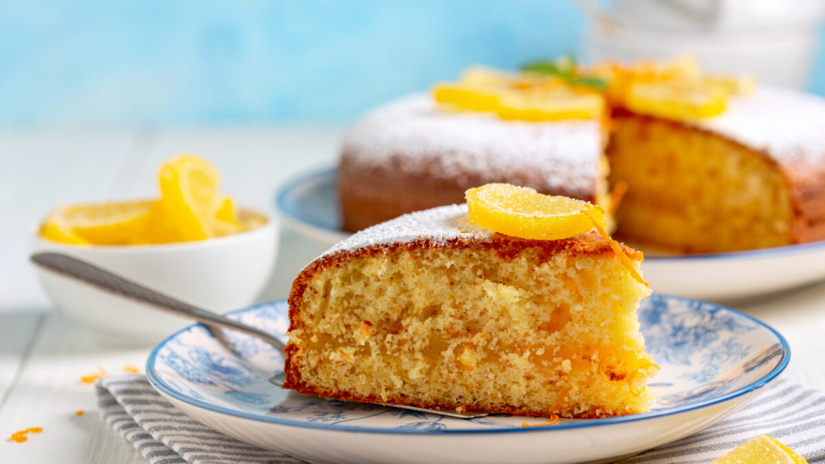 Piece of Italian orange cake is served on a plate with a marmalade decor and a sprig of mint. Concept of traditional homemade Italian pastries.