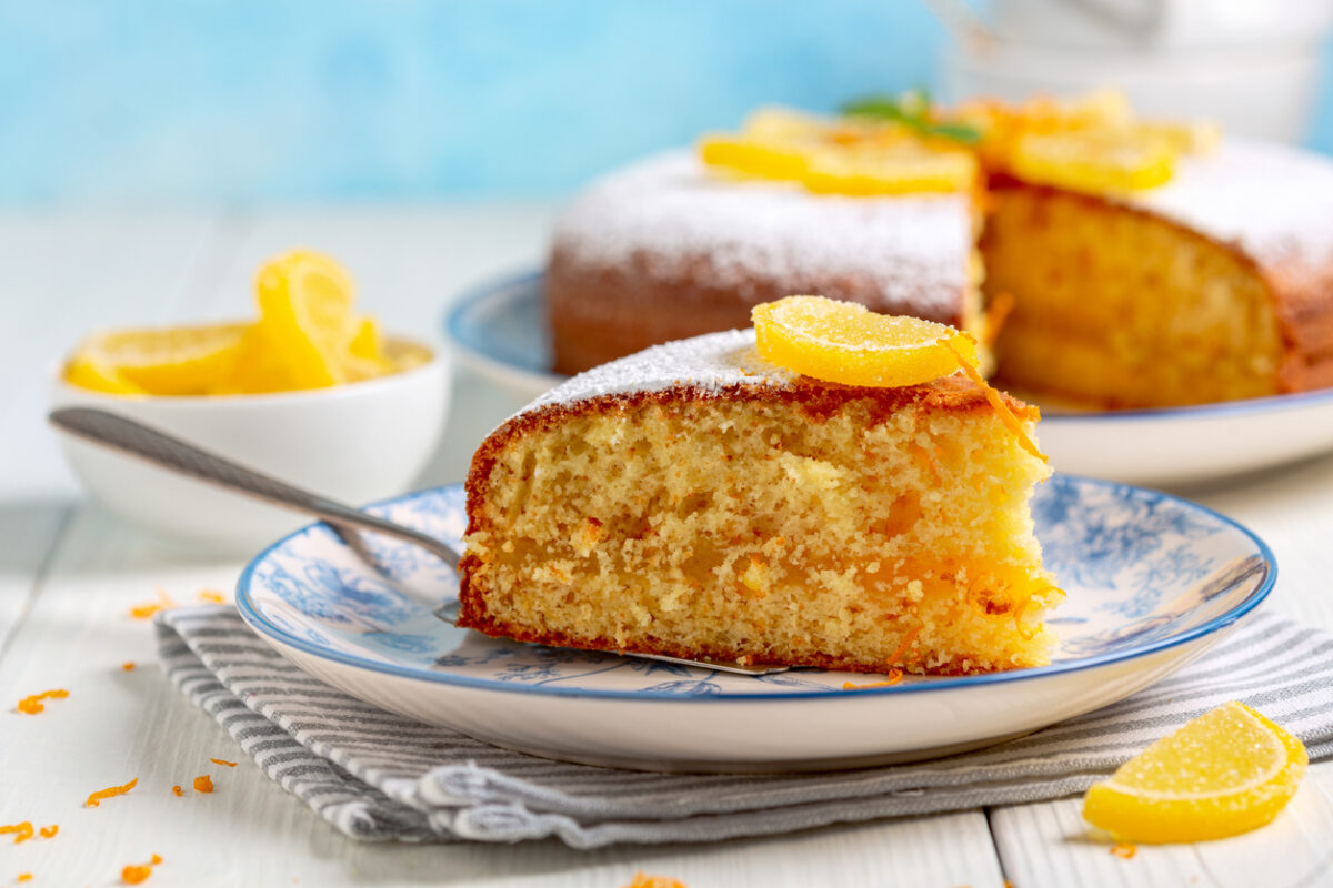 Piece of Italian orange cake is served on a plate with a marmalade decor and a sprig of mint. Concept of traditional homemade Italian pastries.