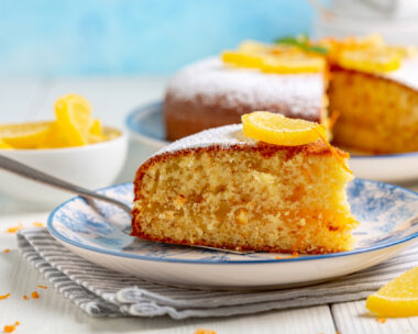 Piece of Italian orange cake is served on a plate with a marmalade decor and a sprig of mint. Concept of traditional homemade Italian pastries.