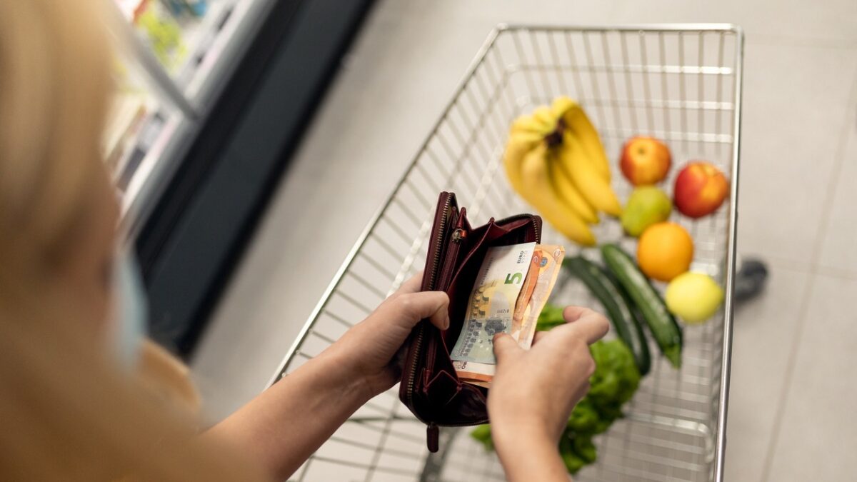 A worried woman checking her wallet when shopping in supermarket. Inflation and economic recession concept.