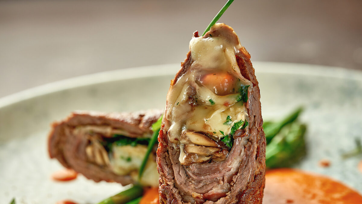Beef wellington with cheese inside, asparagus and sauce. Close-up. Selective focus