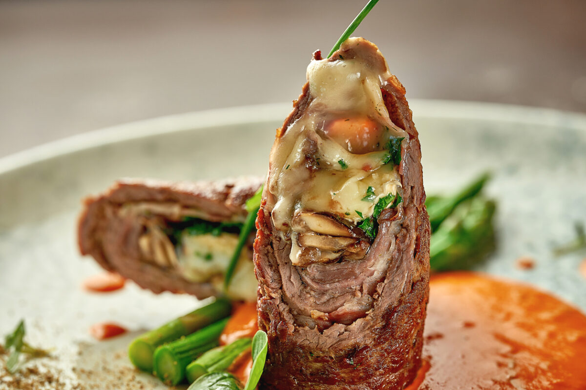 Beef wellington with cheese inside, asparagus and sauce. Close-up. Selective focus