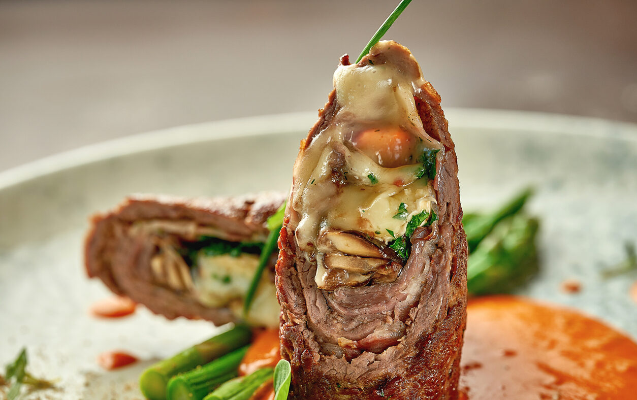 Beef wellington with cheese inside, asparagus and sauce. Close-up. Selective focus