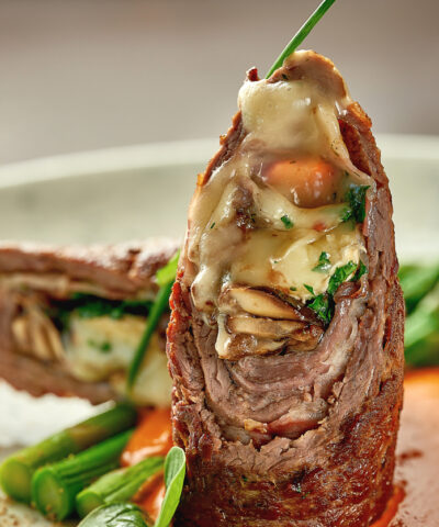 Beef wellington with cheese inside, asparagus and sauce. Close-up. Selective focus