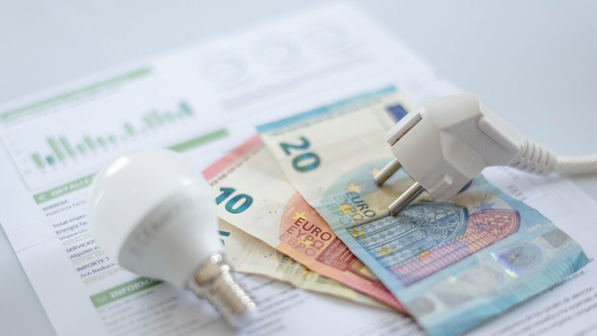 A white electric cap, a light bulb and euro banknotes on an electric bill