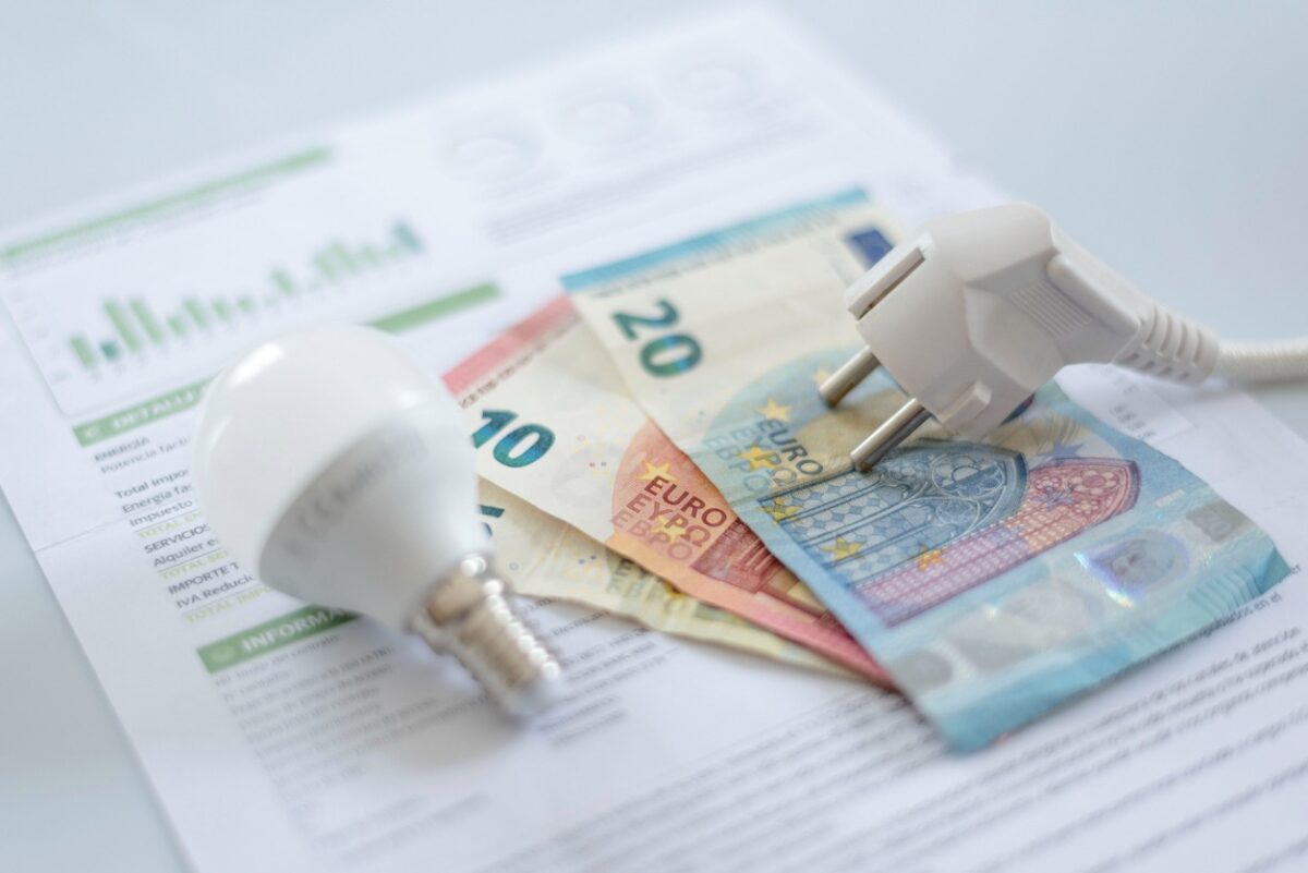 A white electric cap, a light bulb and euro banknotes on an electric bill