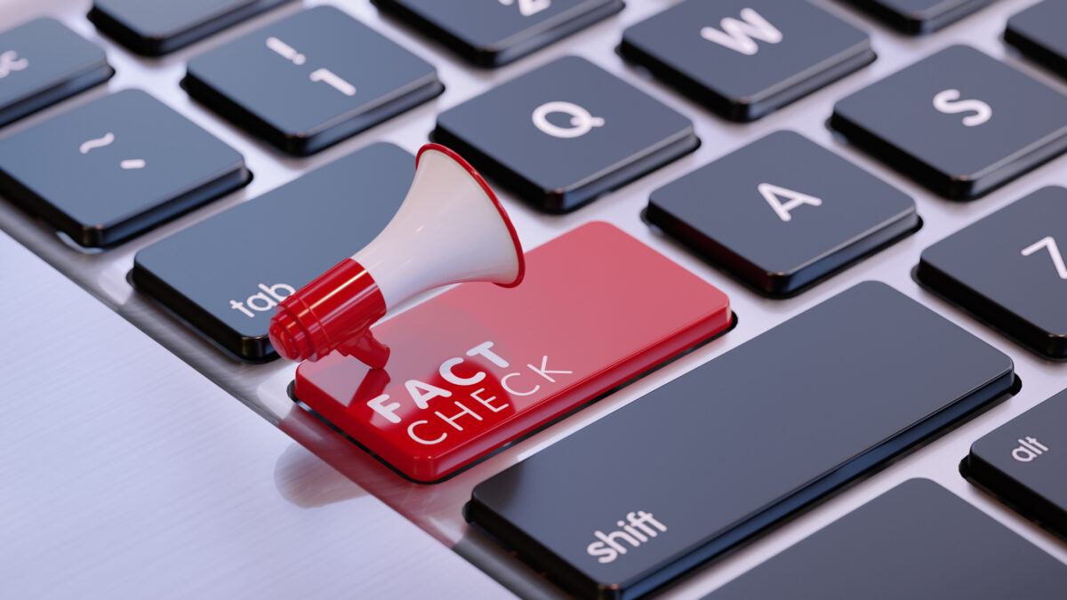 Red megaphone sitting on fact check written computer keyboard
