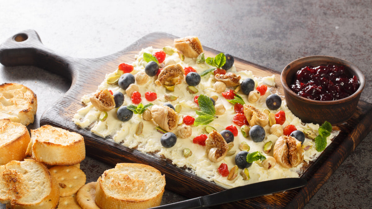 κατσικίσιο τυρί: 10 ουγγιές κατσικίσιο τυρί 1/4 φλιτζάνι απλό γιαούρτι πλήρους γάλακτος 1/4 φλιτζάνι πλήρες γάλα 1/2 λεμόνι, στυμμένο Μια πρέζα αλάτι kosher Για τα υλικά γαρνιρίσματος: 4 φέτες μπέικον, ψημένες μέχρι να γίνουν τραγανές 2 κουταλιές της σούπας μέλι 2 κουταλιές της σούπας χρυσές σταφίδες 2 κουταλιές της σούπας ψιλοκομμένα φιστίκια 2 κουταλιές της σούπας ψιλοκομμένους χουρμάδες ή σύκα 1 κουταλιά της σούπας ηλιόσπορους 1 κουταλιά της σούπας σχοινόπρασο πίτα τσιπς , για το σερβίρισμα Μέθοδος Χτυπήστε το κατσικίσιο τυρί: Σε ένα μεσαίο μπολ, προσθέστε κατσικίσιο τυρί, γιαούρτι, γάλα, χυμό λεμονιού και μια πρέζα αλάτι. Χρησιμοποιήστε ένα μίξερ χειρός ή ένα μίξερ βάσης για να χτυπήσετε το μείγμα κατσικίσιου τυριού μέχρι να αποκτήσει μια λεία, ελαφριά υφή. (Αν δεν έχετε μίξερ χειρός ή μίξερ βάσης, μπορείτε να χρησιμοποιήσετε ένα πιρούνι για να λιώσετε τα υλικά μαζί, αλλά δεν θα έχουν την ίδια σαντιγί υφή.) Η τελική σάλτσα θα πρέπει να απλώνεται εύκολα με ένα μαχαίρι. Αν είναι πολύ πηχτή ή φαίνεται στεγνή, προσθέστε περισσότερο γάλα με κουταλιά της σούπας, χτυπώντας μετά από κάθε προσθήκη. Χτυπήστε κατσικίσιο τυρί σε ένα μπολ από ανοξείδωτο ατσάλι για σως 7 στρώσεων Νικ Έβανς Χτυπήστε το κατσικίσιο τυρί με πιρούνι ή μίξερ χειρός για σως 7 στρώσεων Νικ Έβανς Συναρμολογήστε τη σάλτσα: Απλώστε το χτυπημένο κατσικίσιο τυρί σε μια λεπτή, ομοιόμορφη στρώση κατά μήκος του πάτου ενός ταψιού 2 1/2 λίτρων ή ενός ταψιού 20x20 εκατοστών. Δεν πρέπει να έχει πάχος μεγαλύτερο από 1,25 εκατοστά σε κανένα σημείο της σάλτσας. Ρίξτε το μέλι πάνω από τη σάλτσα και στη συνέχεια πασπαλίστε ομοιόμορφα το μπέικον, τις χρυσές σταφίδες, τα φιστίκια, τους χουρμάδες, τους ηλιόσπορους και το ψιλοκομμένο σχοινόπρασο. Διατηρείται σκεπασμένο στο ψυγείο μέχρι να είναι έτοιμο για κατανάλωση και στη συνέχεια σερβίρεται με τσιπς πίτας. Αυτή η σάλτσα μπορεί εύκολα να γίνει 2 με 3 μέρες νωρίτερα και διατηρείται καλά στο ψυγείο. Αν την φτιάξετε νωρίτερα, περιμένετε λίγο πριν προσθέσετε το μέλι και το σχοινόπρασο μέχρι λίγο πριν τη σερβίρετε.