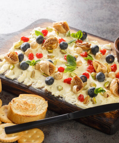 κατσικίσιο τυρί: 10 ουγγιές κατσικίσιο τυρί 1/4 φλιτζάνι απλό γιαούρτι πλήρους γάλακτος 1/4 φλιτζάνι πλήρες γάλα 1/2 λεμόνι, στυμμένο Μια πρέζα αλάτι kosher Για τα υλικά γαρνιρίσματος: 4 φέτες μπέικον, ψημένες μέχρι να γίνουν τραγανές 2 κουταλιές της σούπας μέλι 2 κουταλιές της σούπας χρυσές σταφίδες 2 κουταλιές της σούπας ψιλοκομμένα φιστίκια 2 κουταλιές της σούπας ψιλοκομμένους χουρμάδες ή σύκα 1 κουταλιά της σούπας ηλιόσπορους 1 κουταλιά της σούπας σχοινόπρασο πίτα τσιπς , για το σερβίρισμα Μέθοδος Χτυπήστε το κατσικίσιο τυρί: Σε ένα μεσαίο μπολ, προσθέστε κατσικίσιο τυρί, γιαούρτι, γάλα, χυμό λεμονιού και μια πρέζα αλάτι. Χρησιμοποιήστε ένα μίξερ χειρός ή ένα μίξερ βάσης για να χτυπήσετε το μείγμα κατσικίσιου τυριού μέχρι να αποκτήσει μια λεία, ελαφριά υφή. (Αν δεν έχετε μίξερ χειρός ή μίξερ βάσης, μπορείτε να χρησιμοποιήσετε ένα πιρούνι για να λιώσετε τα υλικά μαζί, αλλά δεν θα έχουν την ίδια σαντιγί υφή.) Η τελική σάλτσα θα πρέπει να απλώνεται εύκολα με ένα μαχαίρι. Αν είναι πολύ πηχτή ή φαίνεται στεγνή, προσθέστε περισσότερο γάλα με κουταλιά της σούπας, χτυπώντας μετά από κάθε προσθήκη. Χτυπήστε κατσικίσιο τυρί σε ένα μπολ από ανοξείδωτο ατσάλι για σως 7 στρώσεων Νικ Έβανς Χτυπήστε το κατσικίσιο τυρί με πιρούνι ή μίξερ χειρός για σως 7 στρώσεων Νικ Έβανς Συναρμολογήστε τη σάλτσα: Απλώστε το χτυπημένο κατσικίσιο τυρί σε μια λεπτή, ομοιόμορφη στρώση κατά μήκος του πάτου ενός ταψιού 2 1/2 λίτρων ή ενός ταψιού 20x20 εκατοστών. Δεν πρέπει να έχει πάχος μεγαλύτερο από 1,25 εκατοστά σε κανένα σημείο της σάλτσας. Ρίξτε το μέλι πάνω από τη σάλτσα και στη συνέχεια πασπαλίστε ομοιόμορφα το μπέικον, τις χρυσές σταφίδες, τα φιστίκια, τους χουρμάδες, τους ηλιόσπορους και το ψιλοκομμένο σχοινόπρασο. Διατηρείται σκεπασμένο στο ψυγείο μέχρι να είναι έτοιμο για κατανάλωση και στη συνέχεια σερβίρεται με τσιπς πίτας. Αυτή η σάλτσα μπορεί εύκολα να γίνει 2 με 3 μέρες νωρίτερα και διατηρείται καλά στο ψυγείο. Αν την φτιάξετε νωρίτερα, περιμένετε λίγο πριν προσθέσετε το μέλι και το σχοινόπρασο μέχρι λίγο πριν τη σερβίρετε.