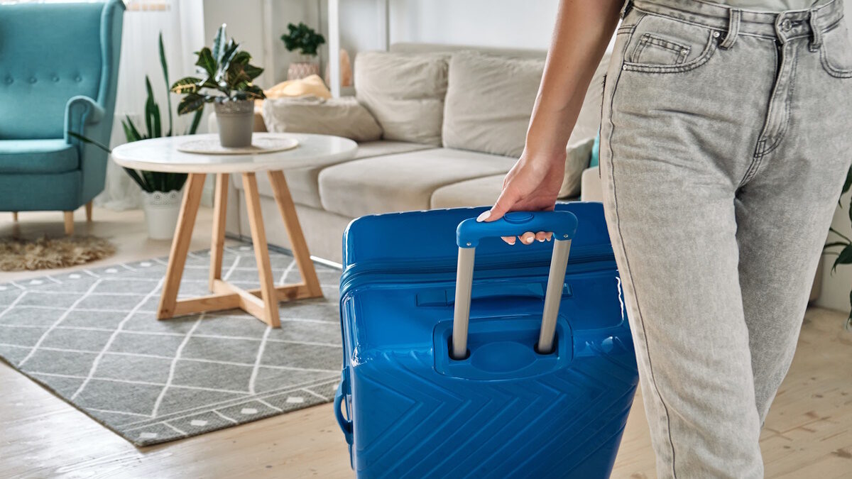 Unrecognizable woman leaving home with a suitcase going on a trip or vacation.