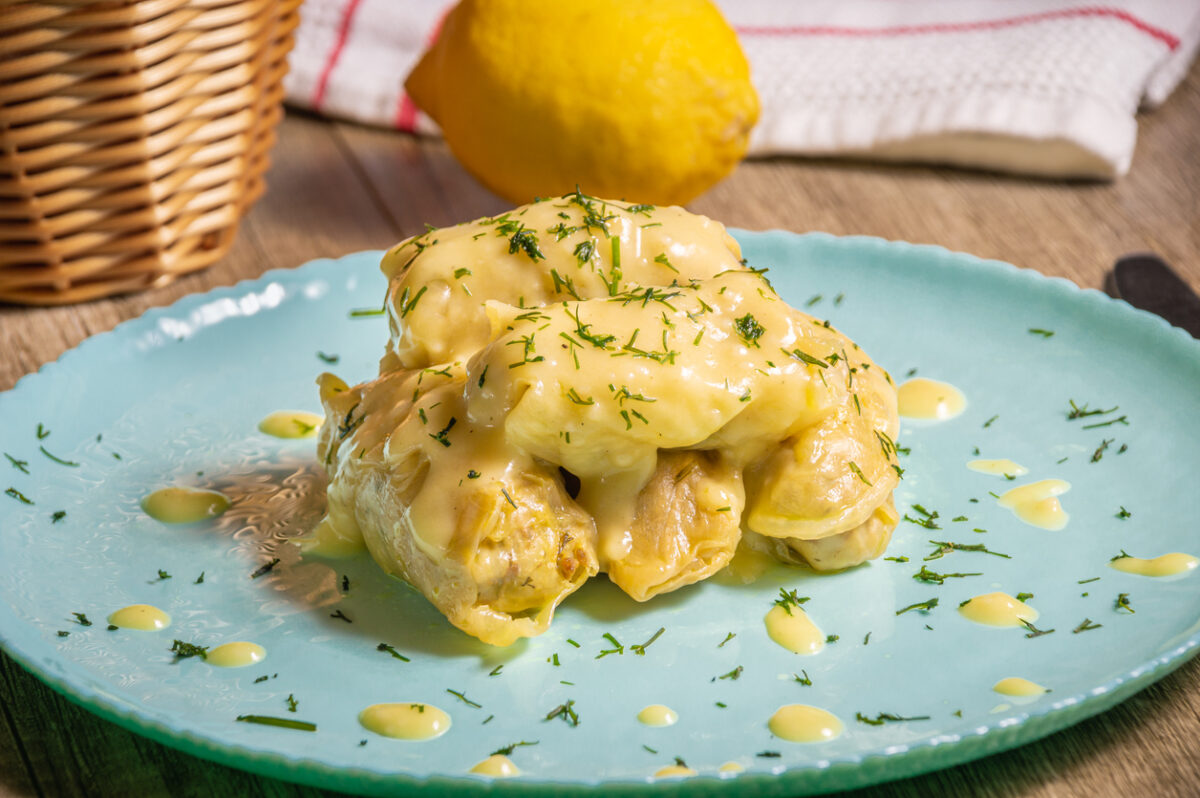 Traditional Greek cabbage rolls (Lahanodolmades) with ground beef, rice and cream sauce on a wooden table