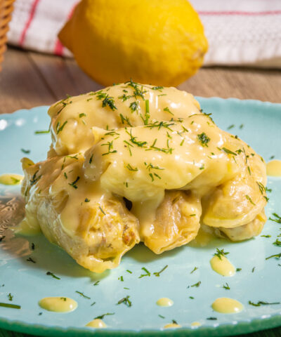 Traditional Greek cabbage rolls (Lahanodolmades) with ground beef, rice and cream sauce on a wooden table