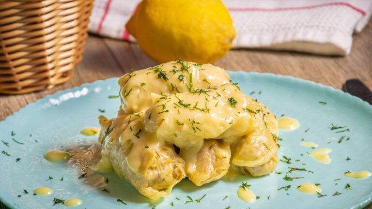 Traditional Greek cabbage rolls (Lahanodolmades) with ground beef, rice and cream sauce on a wooden table