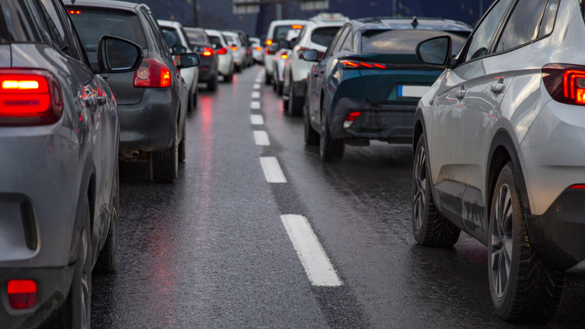 Traffic jam with a row of cars on a highway during rush hour in the evening after work. red brake lights of stopped cars on the background of wet asphalt with white lanes at sunset