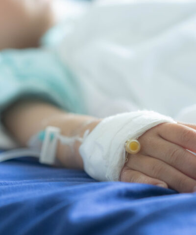 an Asian todler in hospital with intravenous saline. Sick children, infected with the virus, are lying and being treated in beds in hospitals.