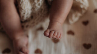 Sweet little feet of newborn baby on beige background, baby care and parenthood concept