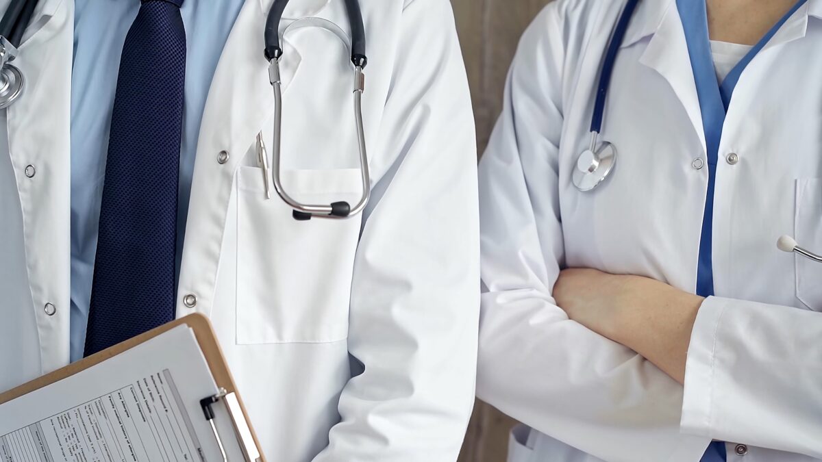 Professional healthcare team in uniform. Two doctors with stethoscopes are standing straight with arms crossed. Medicine concept.