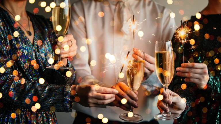 Friends celebrating Christmas or New Year eve party with Bengal lights and champagne.