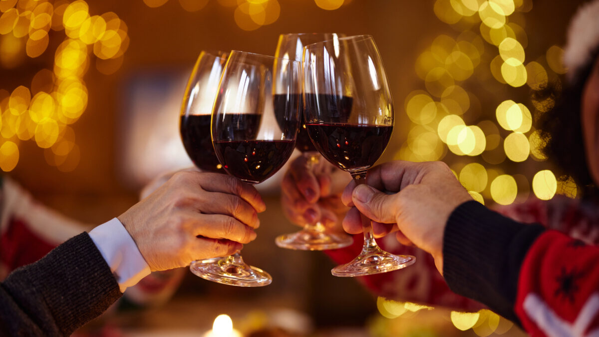 Close up of unrecognizable mature friends toasting with red wine during Christmas party at home