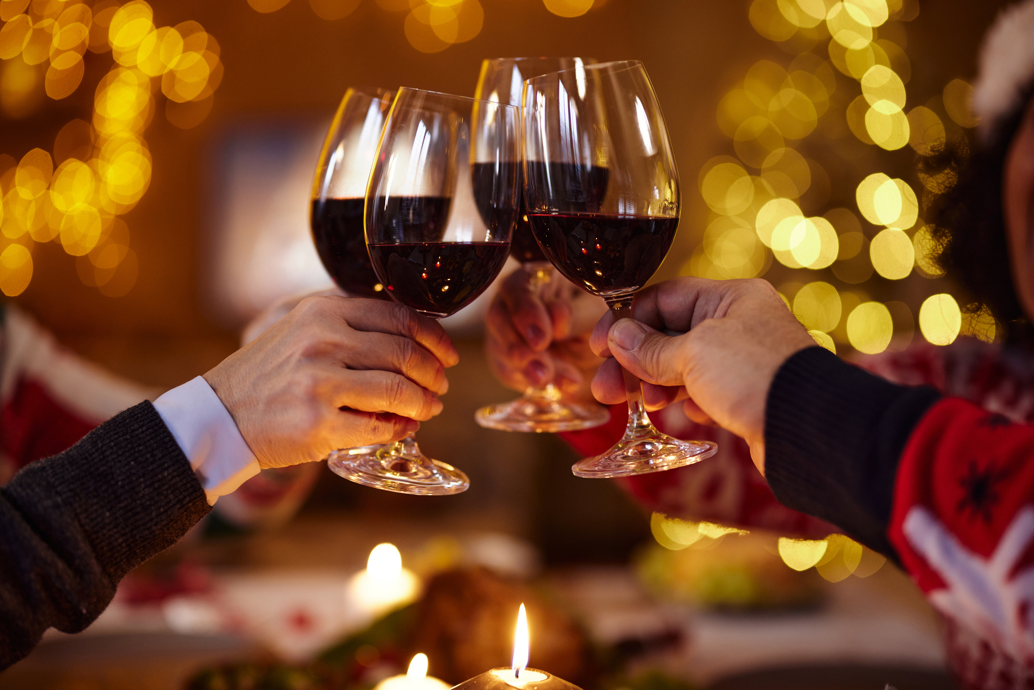 Close up of unrecognizable mature friends toasting with red wine during Christmas party at home