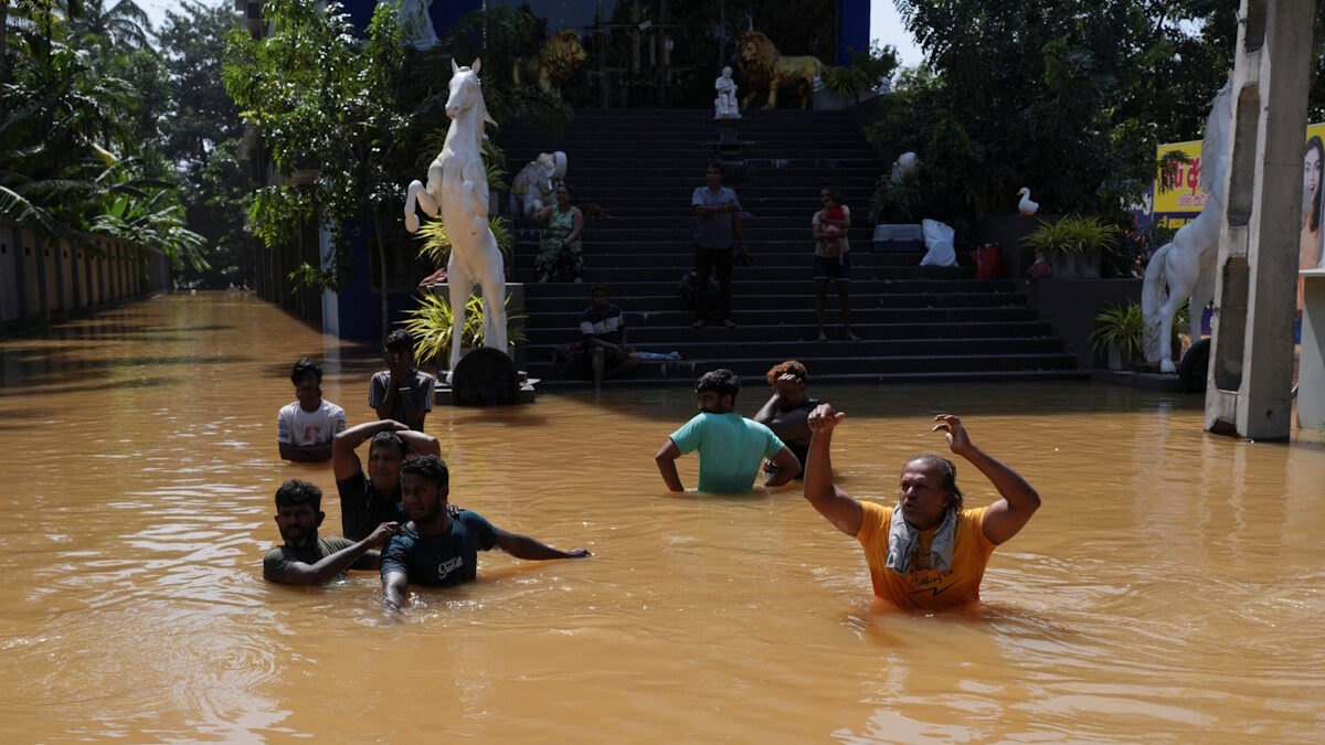 Άνθρωποι περπατούν μέσα σε πλημμυρισμένο δρόμο, μετά τον κυκλώνα Ditwah στην Κελάνια της Σρι Λάνκα