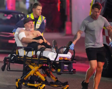 Εργαζόμενοι των υπηρεσιών έκτακτης ανάγκης μεταφέρουν ένα άτομο σε φορείο μετά από αναφορά για πυροβολισμούς στην παραλία Bondi Beach στο Σίδνεϊ