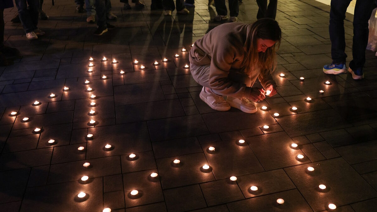 Μια γυναίκα ανάβει ένα κερί για να το τοποθετήσει σε μια σύνθεση σε σχήμα Αστέρα του Δαυίδ κατά τη διάρκεια αγρυπνίας κοντά στην παραλία, που πραγματοποιήθηκε μετά από ένα θανατηφόρο πυροβολισμό στην παραλία Bondi του Σίδνεϊ κατά τη διάρκεια των εορτασμών του Χανουκά, στο Τελ Αβίβ