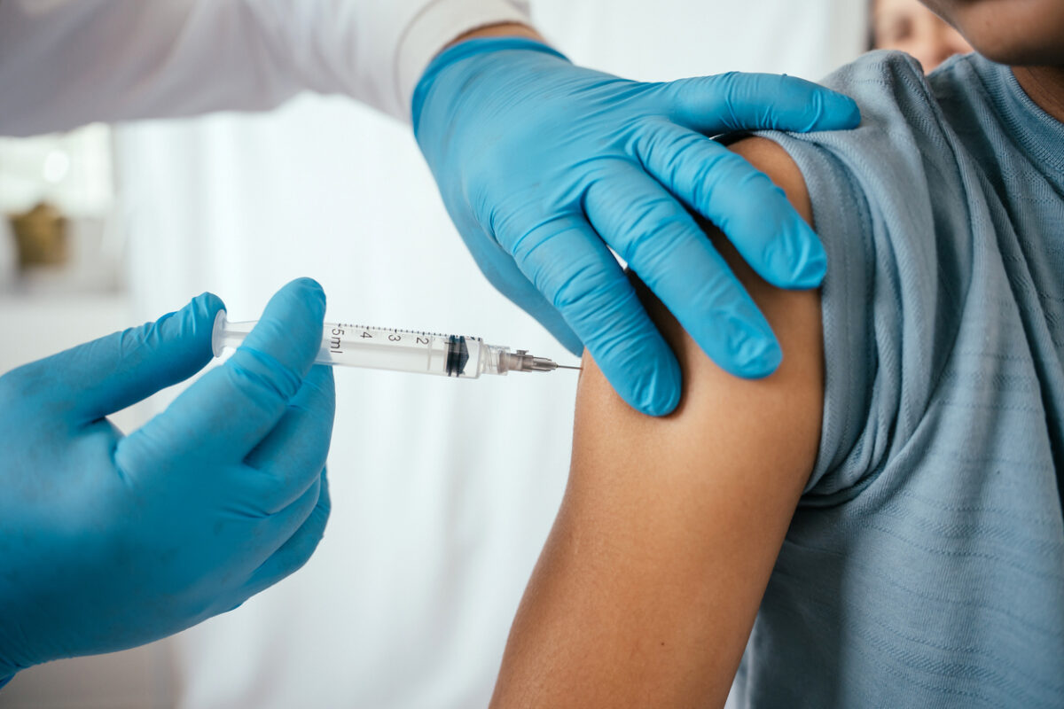 Doctor administering vaccine to teenager in doctor's office
