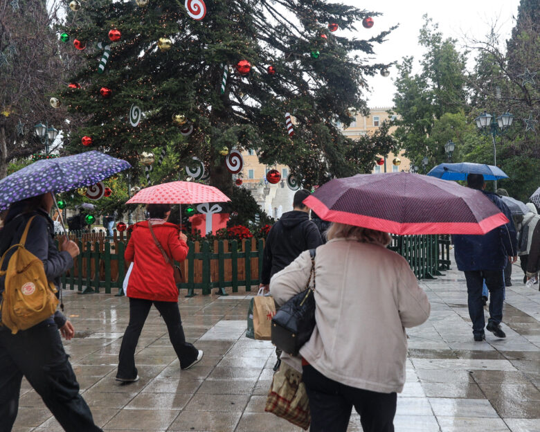 άνθρωποι με ομπρέλες μπροστά από το Χριστουγεννιάτικο δέντρο στο Σύνταγμα
