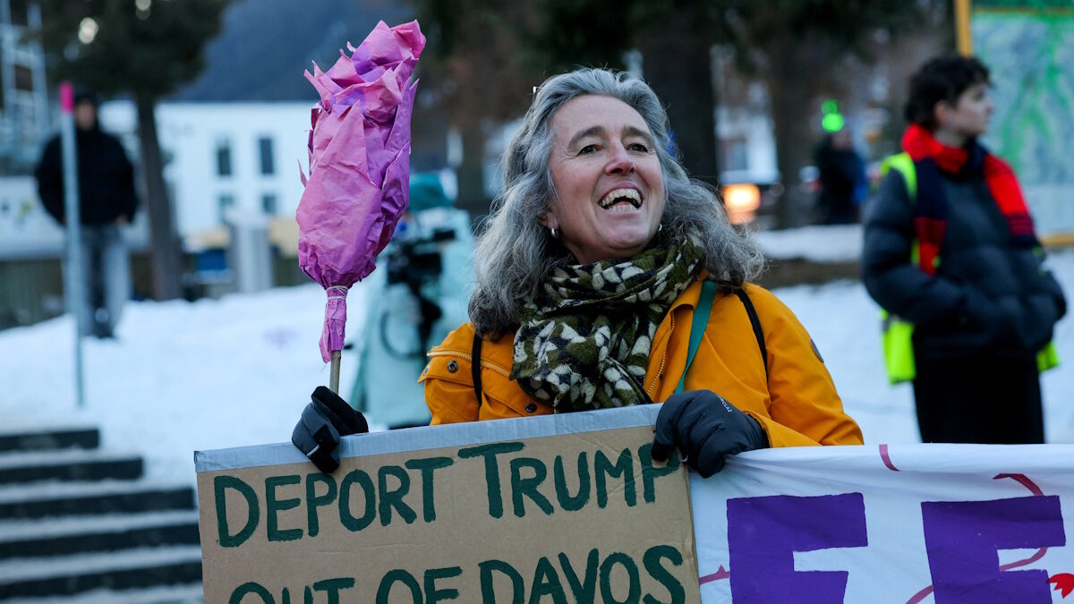 An activist holds a placard with a slogan against U.S. President Donald Trump, during a protest, ahead of the opening of the World Economic Forum (WEF), in Davos, Switzerland, January 18, 2026.