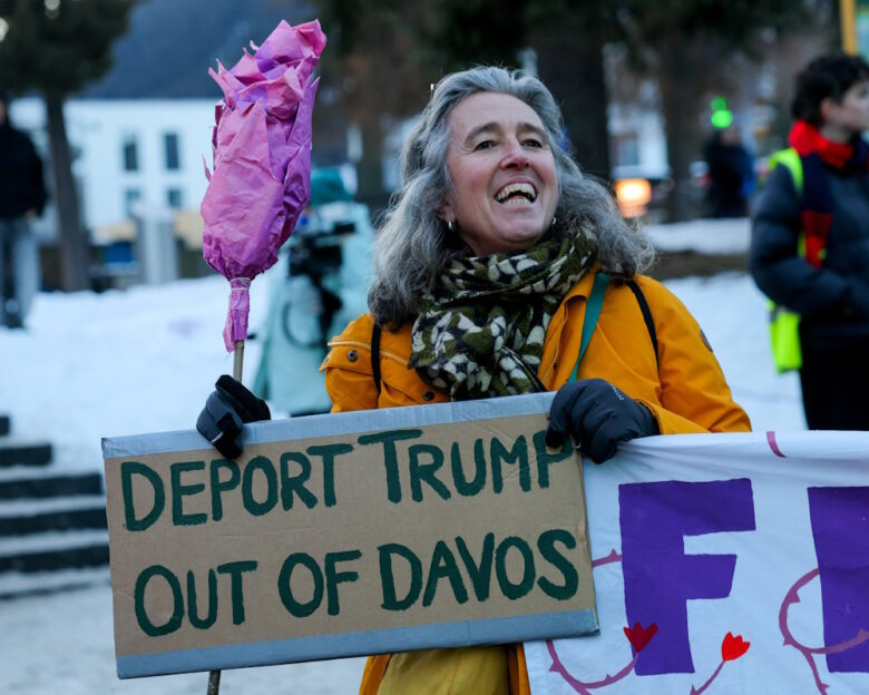 An activist holds a placard with a slogan against U.S. President Donald Trump, during a protest, ahead of the opening of the World Economic Forum (WEF), in Davos, Switzerland, January 18, 2026.