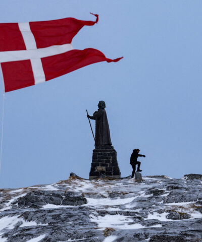 Δανική σημαία κυματίζει δίπλα στο άγαλμα του Χανς Έγκεντε στο Νουούκ της Γροιλανδίας