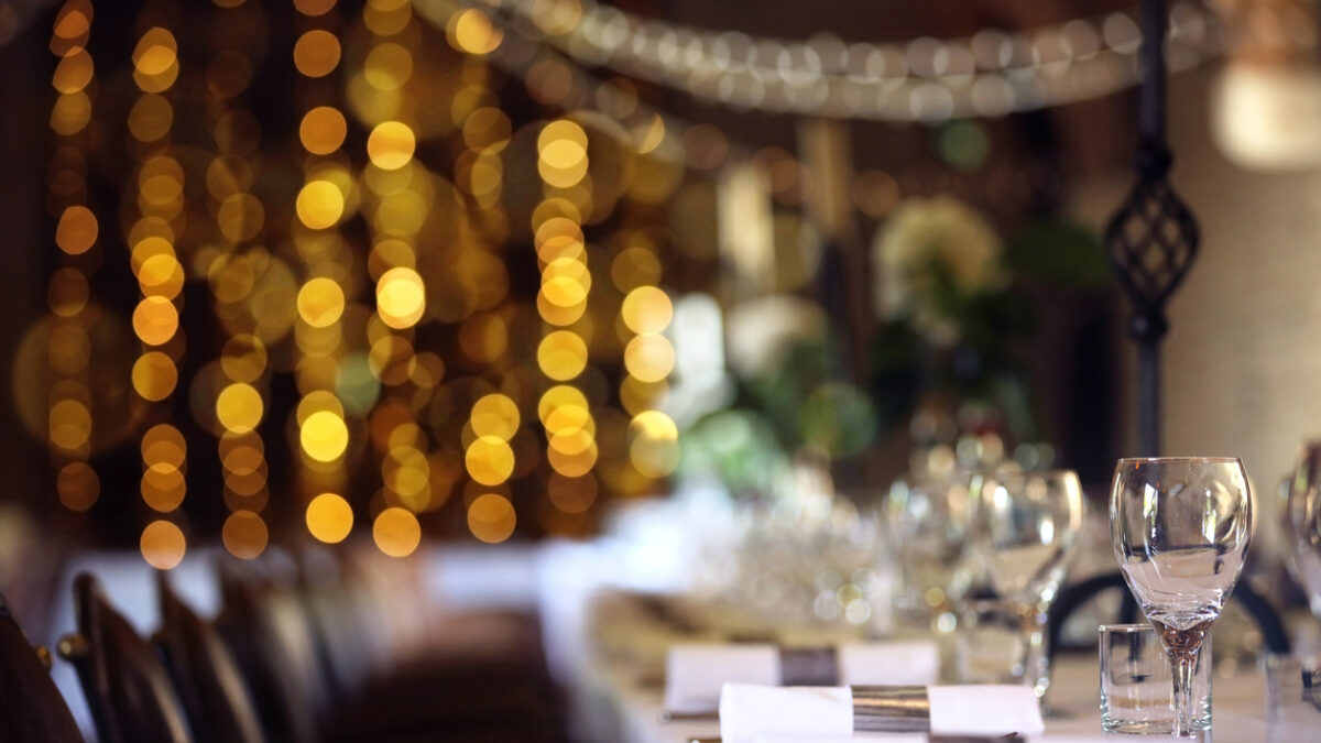 Formal wedding place setting on long table background focus on wine glass