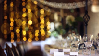 Formal wedding place setting on long table background focus on wine glass