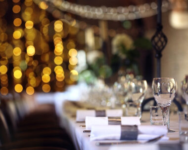 Formal wedding place setting on long table background focus on wine glass