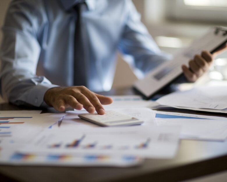 Business accounting concept, Business man using calculator with computer laptop, budget and loan paper in office.