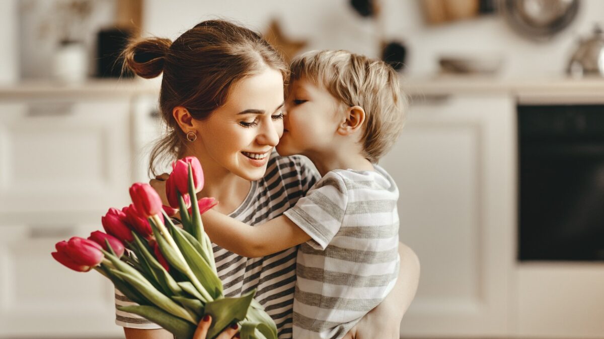 happy mother's day! child son congratulates mother on holiday and gives flowers