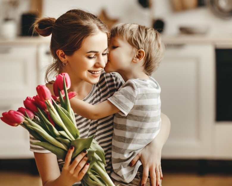 happy mother's day! child son congratulates mother on holiday and gives flowers