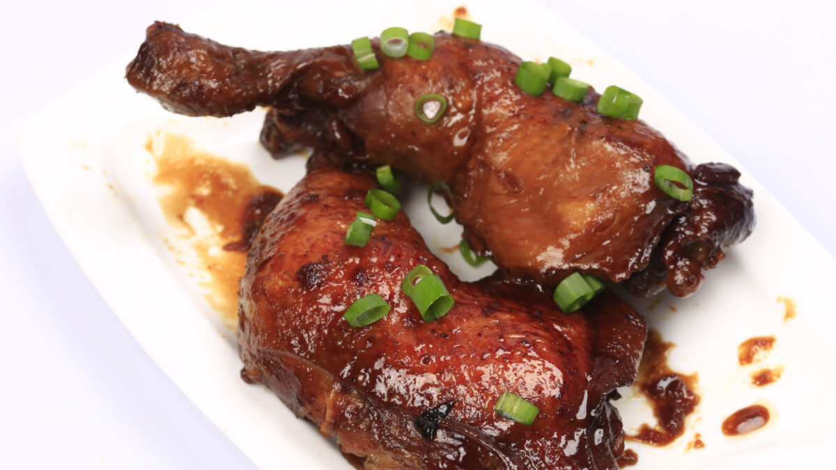 Baked chicken legs in spicy glaze with honey sauce on the plate, white background