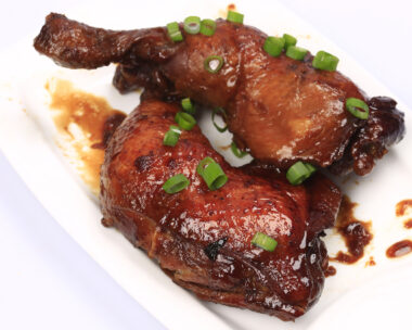 Baked chicken legs in spicy glaze with honey sauce on the plate, white background