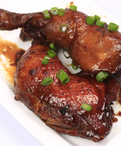 Baked chicken legs in spicy glaze with honey sauce on the plate, white background