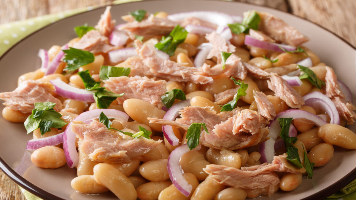 Hearty homemade salad with tuna, onions and white beans close-up in a plate on the table. horizontal
