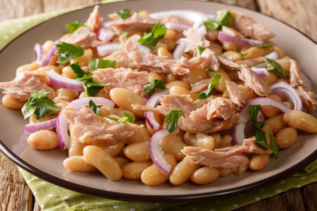 Hearty homemade salad with tuna, onions and white beans close-up in a plate on the table. horizontal