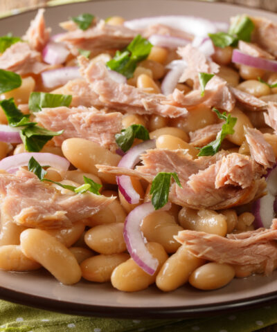 Hearty homemade salad with tuna, onions and white beans close-up in a plate on the table. horizontal