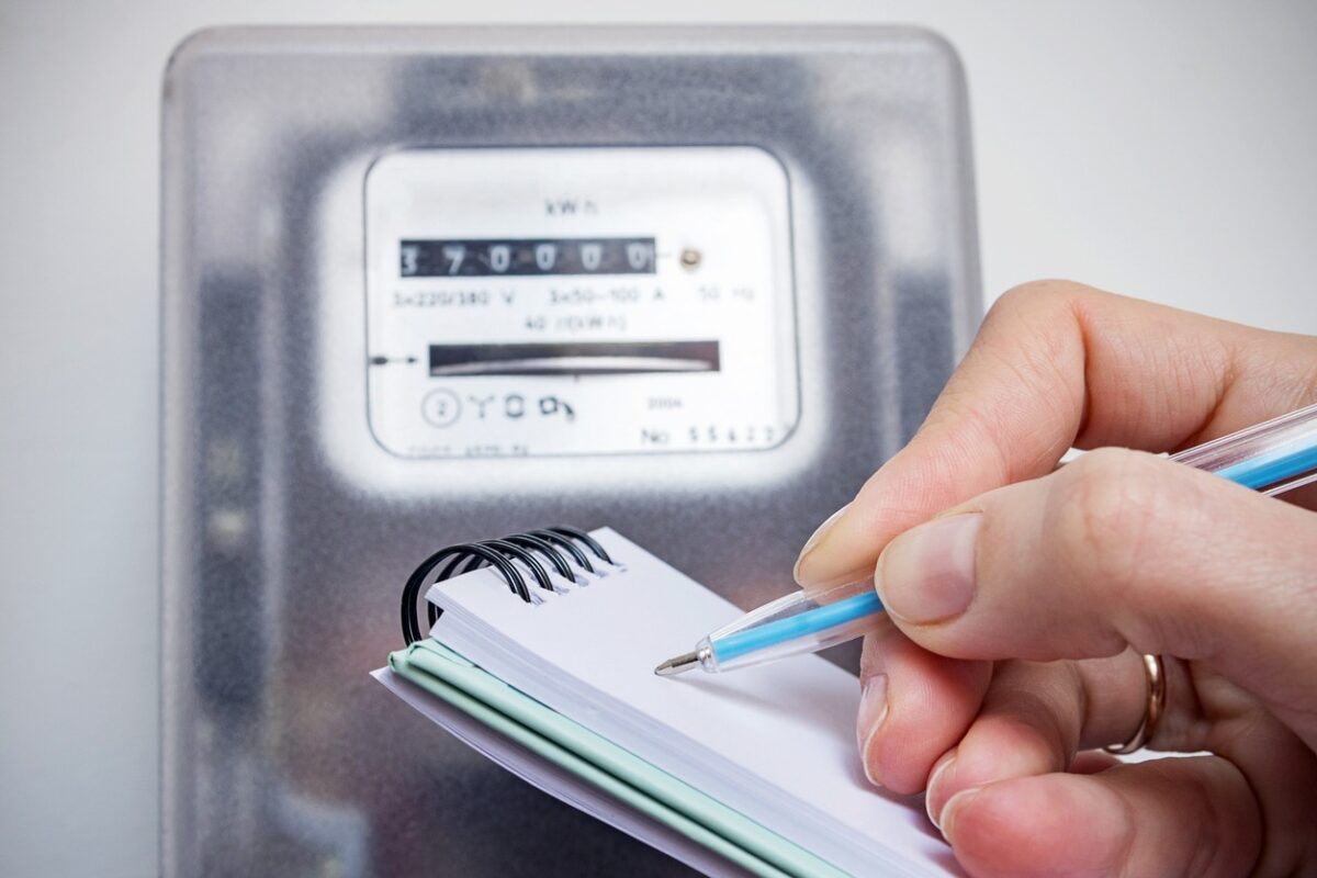 Woman with pen and notepad writes the electricity meter readings. Payment of utility services