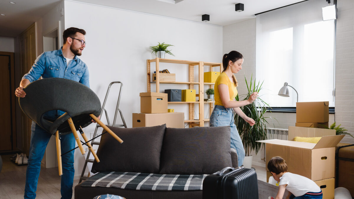 Happy young family husband, wife and toddler son just moved into new home unpacking. Relocation.