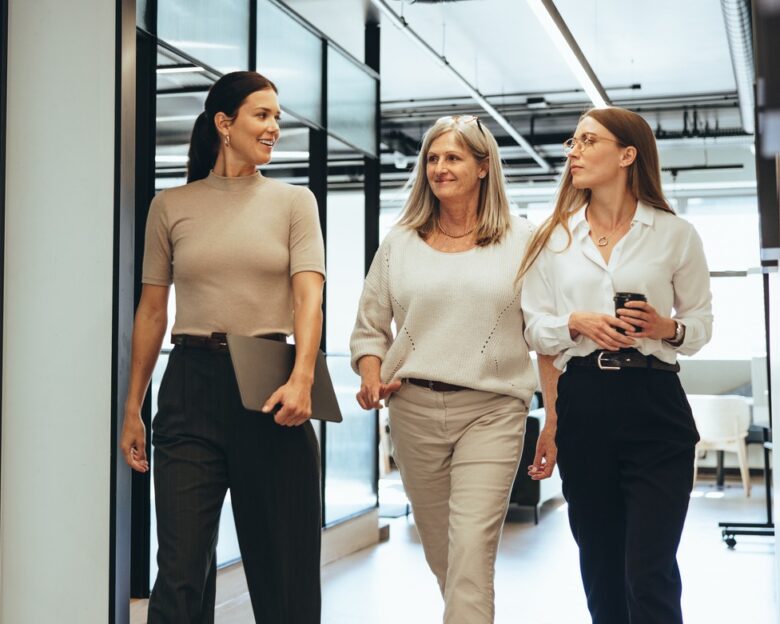 Three cheerful businesswomen walking together in an office. Diverse group of businesswomen smiling while having a discussion. Successful female colleagues collaborating on a new project