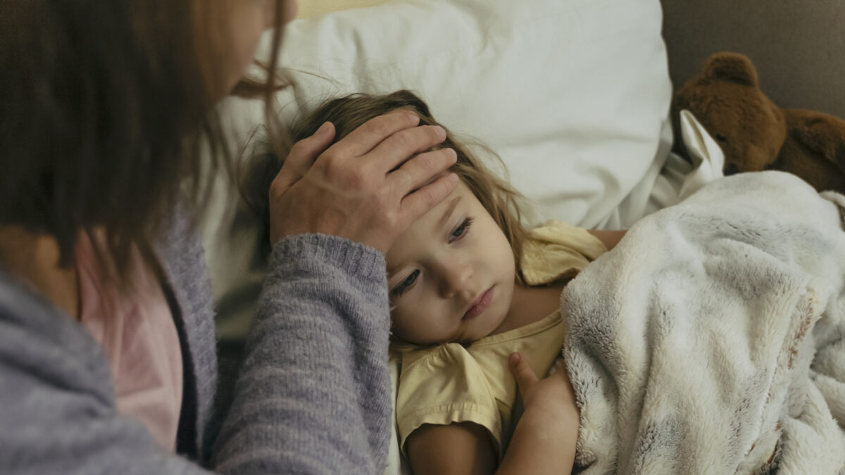 Portrait of sad engrossed sick little girl and her mother touching daughter's forehead.