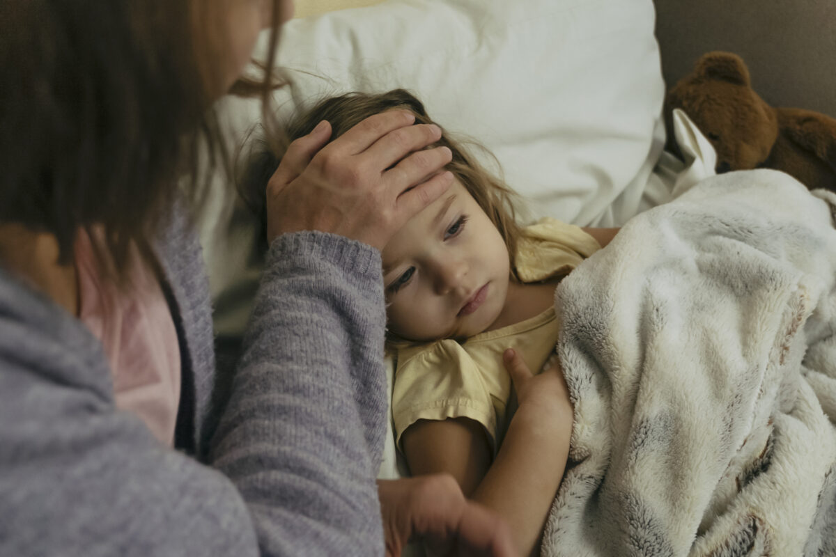 Portrait of sad engrossed sick little girl and her mother touching daughter's forehead.