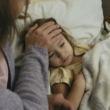 Portrait of sad engrossed sick little girl and her mother touching daughter's forehead.